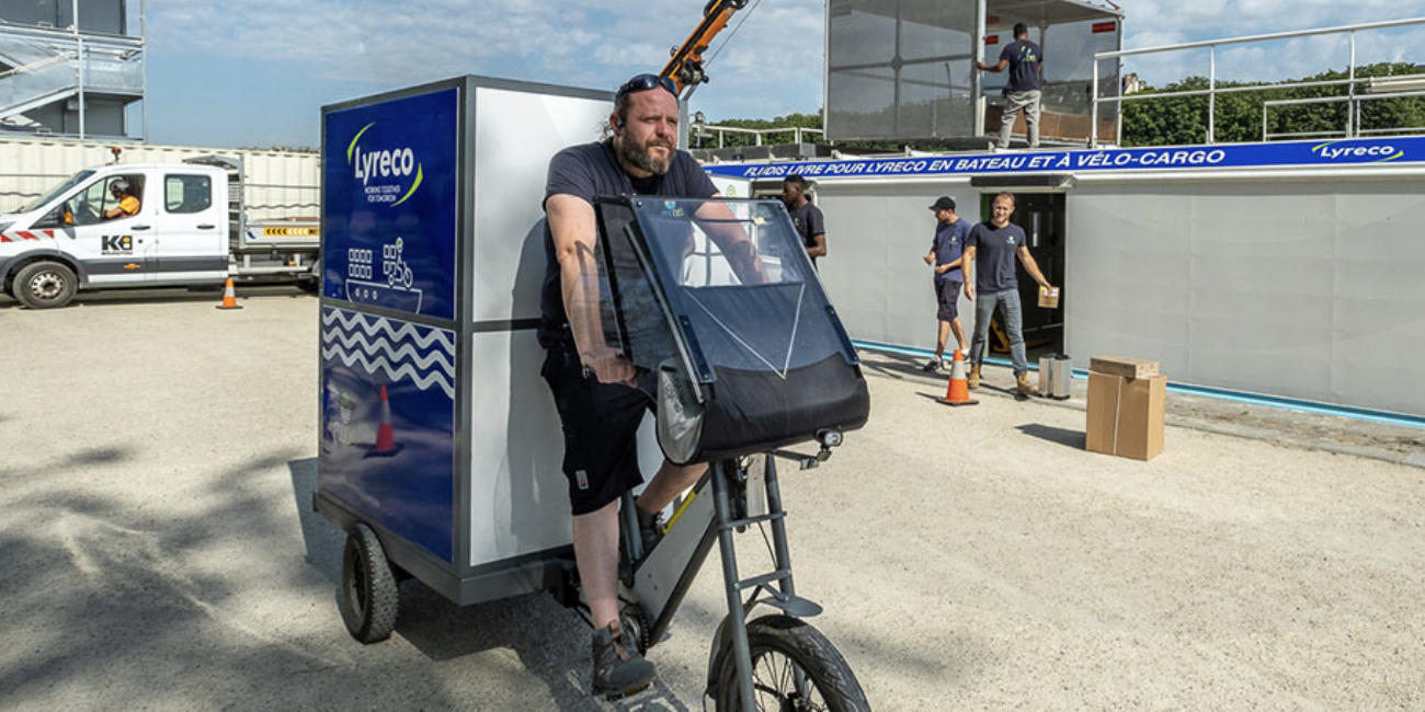 Livraison à vélo Livreur en vélo cargo devant une barge