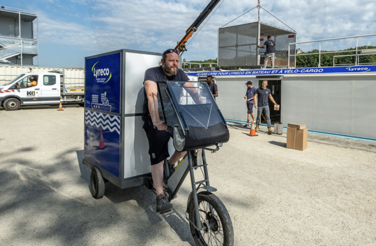 Livraison à vélo Livreur en vélo cargo devant une barge