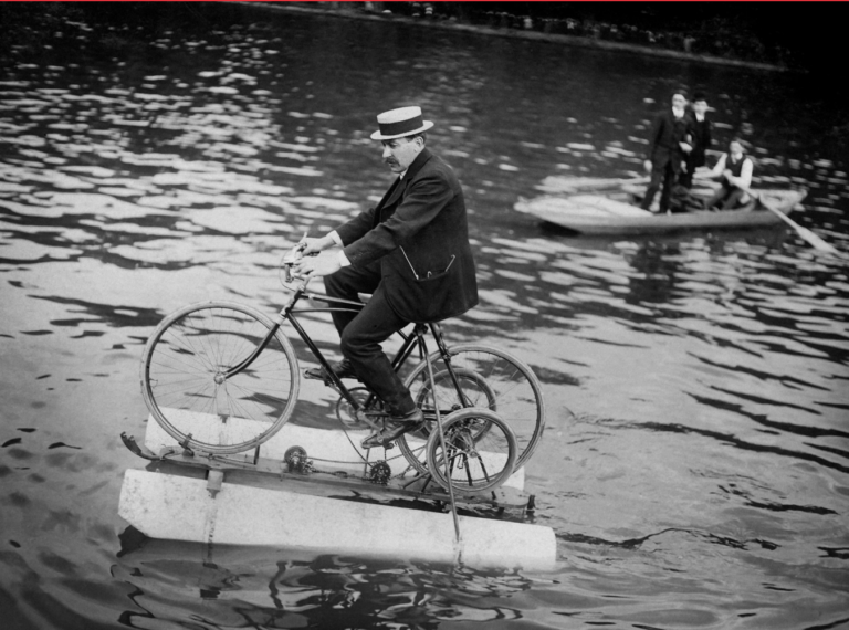 Visuel expo La Seine, la Sine Le visuel de l'exposition montre un homme sur une bicyclette amphibie sur la Seine.